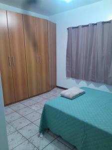 1 dormitorio con cama verde y armarios de madera en Casa Trindade UFSC, en Florianópolis