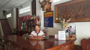 a woman sitting at a counter in a restaurant at Thaveesinh Hotel in Ban Houayxay