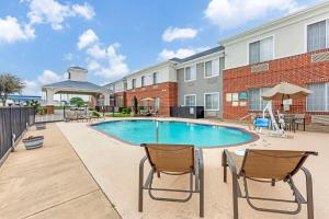 una piscina con 2 sillas y un edificio en Best Western Fort Worth Inn and Suites en Fort Worth