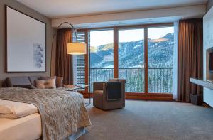 Cette chambre comprend un lit et une grande fenêtre. dans l'établissement Kempinski Hotel Berchtesgaden, à Berchtesgaden