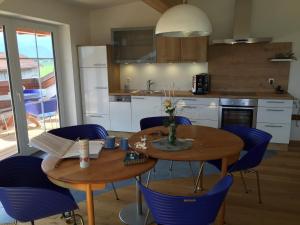 a kitchen with two wooden tables and blue chairs at Alpenglück de Luxe Ferienwohnung am Forggensee in Schwangau