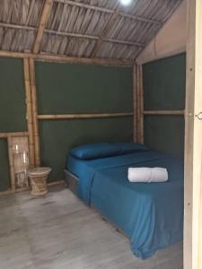 a bedroom with a blue bed with a towel on it at El Puente in Sipacate