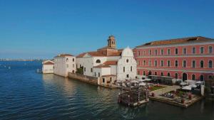 eine Gruppe von Gebäuden neben dem Wasser mit einem Boot in der Unterkunft San Clemente Palace Kempinski Venice in Venedig