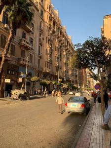 een persoon die een straat oversteekt in een stad met een auto bij TUT Hotel Downtown in Caïro