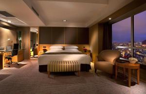 a bedroom with a bed and a desk and a window at Kempinski Hotel Dalian in Dalian