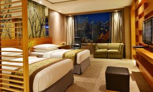 大連市にあるケンピンスキー ホテル 大連のベッド2台とソファが備わるホテルルームです。