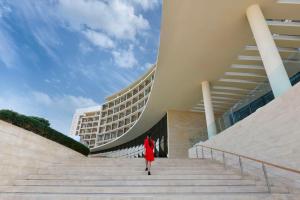 Una donna con un vestito rosso che scende le scale di fronte a un edificio di Kempinski Hotel Aqaba ad Aqaba