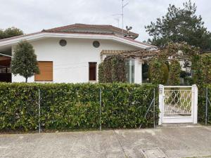 uma casa branca com um portão em frente a uma sebe em Apartment in Bibione 49968 em Bibione