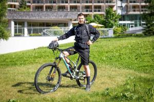 Ein Mann steht neben einem Fahrrad im Gras in der Unterkunft Kempinski Hotel Das Tirol in Jochberg