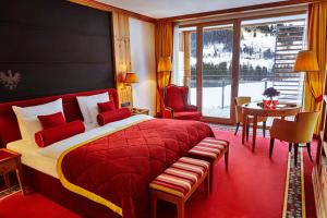 1 dormitorio con cama roja, mesa y sillas en Kempinski Hotel Das Tirol, en Jochberg