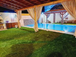 une maison avec une piscine et une pelouse verdoyante dans l'établissement Villa piscine 4 chambres, à Hennchir Ksar Rhaleb