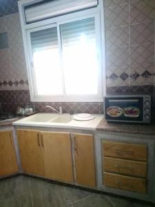 um balcão de cozinha com um lavatório e uma janela em Villa piscine 4 chambres em Hanshīr Qaşr Ghallāb