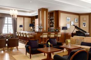 - un salon avec un piano, des tables et des chaises dans l'établissement Grand Hotel Kempinski High Tatras, à Štrbské Pleso