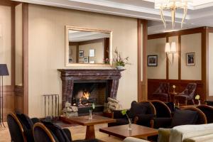 a lobby with a fireplace and chairs and a mirror at Grand Hotel Kempinski High Tatras in Vysoke Tatry - Strbske Pleso