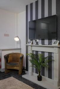 a living room with a tv and a chair and a plant at Vicarage House in Blackpool