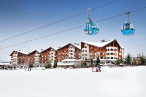 a ski resort with a ski lift in the snow at Kempinski Hotel Grand Arena Bansko in Bansko