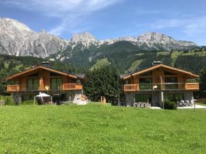 a couple of buildings in a field with mountains in the background at Schneeflocke Leogang in Leogang