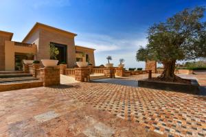 une terrasse en briques avec un arbre en face d'un bâtiment dans l'établissement Kempinski Hotel Ishtar Dead Sea, à Sowayma