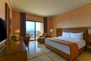 a hotel room with a bed and a balcony at Kempinski Hotel Ishtar Dead Sea in Sowayma