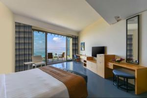 una camera d'albergo con letto, scrivania e TV di Kempinski Hotel Ishtar Dead Sea a Sowayma