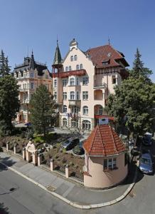 a large brick building with a clock on the side of it at Lazensky Hotel Villa Smetana in Karlovy Vary