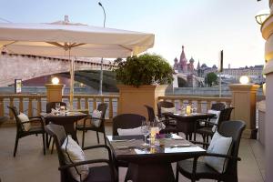 a restaurant with tables and chairs on a balcony at Hotel Baltschug Kempinski Moscow in Moscow