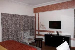 a bedroom with a bed and a tv and a chair at Sandralia Hotel in Abuja