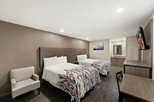 a hotel room with two beds and a chair at Red Roof Inn Nacogdoches in Nacogdoches +27 photos
