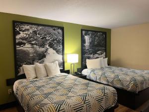 2 camas en una habitación de hotel con carteles en la pared en Motel 6 Forsyth, GA Tift College, en Forsyth