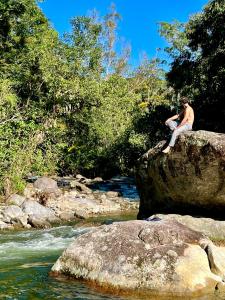 um homem sentado numa rocha ao lado de um rio em Pousada Céu Aberto - Visconde de Mauá - Maringá MG em Itatiaia