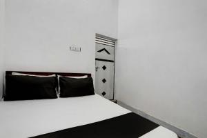 a bedroom with a white bed with black pillows at OYO New River View in Jhājhar