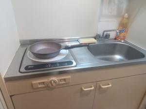 a kitchen with a sink and a frying pan on a stove at リリープロスパー泉 in Aoichō