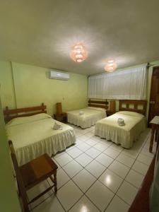 a bedroom with two beds and a tiled floor at Nakum Hotel in Flores