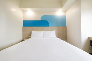 Un dormitorio con una cama blanca y una pintura azul en Hop Inn Hotel North EDSA Quezon City, en Manila