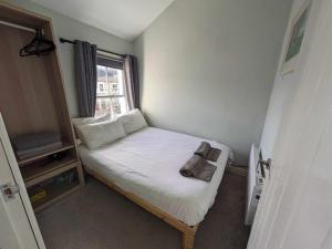 ein kleines Bett in einem kleinen Zimmer mit Fenster in der Unterkunft Converted Railway Cottage in Swindon