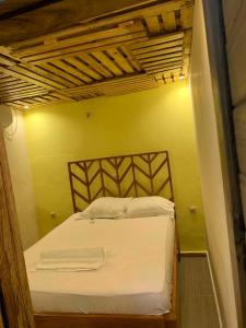 a bedroom with a white bed with a yellow wall at ETOUDI in Douala