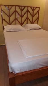 un letto chiuso con lenzuola e cuscini bianchi di ETOUDI a Douala