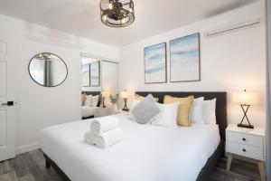 a white bedroom with a large bed and a chair at 3 Bed House with Fire Pit Table and BBQ - Downtown in San Diego