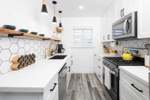 a white kitchen with white countertops and a sink at 3 Bed House with Fire Pit Table and BBQ - Downtown in San Diego