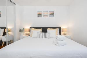 a white bedroom with a large bed with white pillows at 2 Bedroom - Ocean View Hot Tub Parking - 8 Guest in San Diego