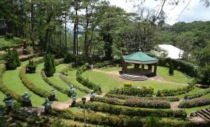 a garden with a gazebo in the middle at Private Rooms and Cabins in Camp John Hay Baguio in Baguio