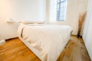 - un lit blanc dans une chambre blanche dotée d'une fenêtre dans l'établissement Le Petit Cocon - Pause douceur, à Cambrai