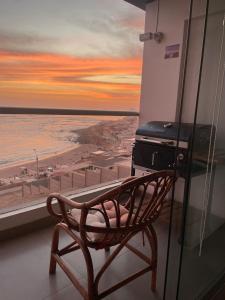 une chaise sur un balcon avec vue sur l'océan dans l'établissement Apartamento Playa Señoritas, à Punta Hermosa