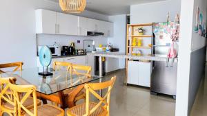 Il comprend une cuisine équipée d'une table en verre et d'un réfrigérateur. dans l'établissement Apartamento Playa Señoritas, à Punta Hermosa