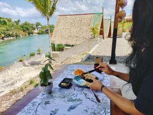 une femme assise à une table avec une assiette de nourriture dans l'établissement Riu del Mar Hostel, à Dauis
