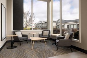 ein Wartezimmer mit Stühlen, Tischen und Fenstern in der Unterkunft Holiday Inn Ontario, an IHG Hotel in Ontario