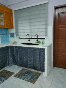 uma cozinha com um lavatório e uma janela em Homestay Ummie 