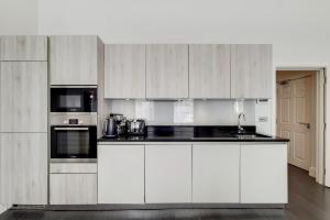 uma cozinha com armários brancos e bancadas pretas em Marylebone - MCR Residences em Londres