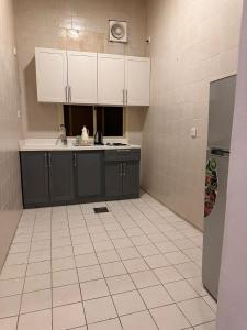 a kitchen with black cabinets and a white tile floor at شقق ارجان نجد المفروشه in Al Nairyah