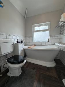 ein Bad mit einer Badewanne, einem WC und einem Fenster in der Unterkunft Tayy’s Inn in Birmingham